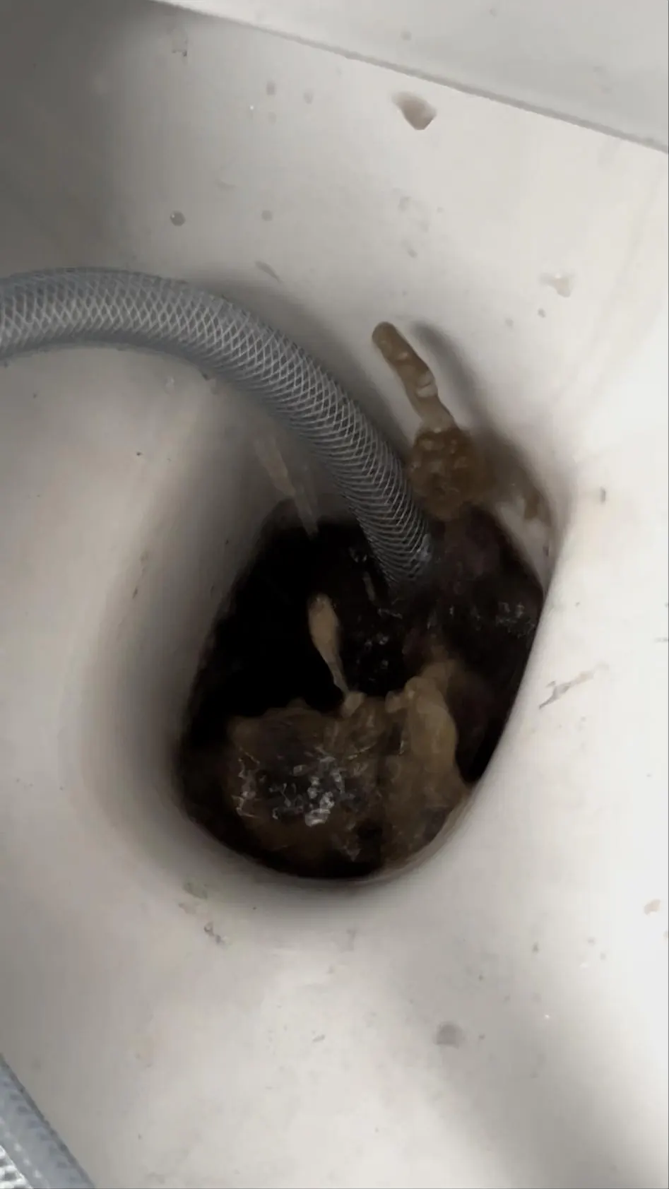 Hrudky černého kalu vyplaveného z trubek podlahového topení
